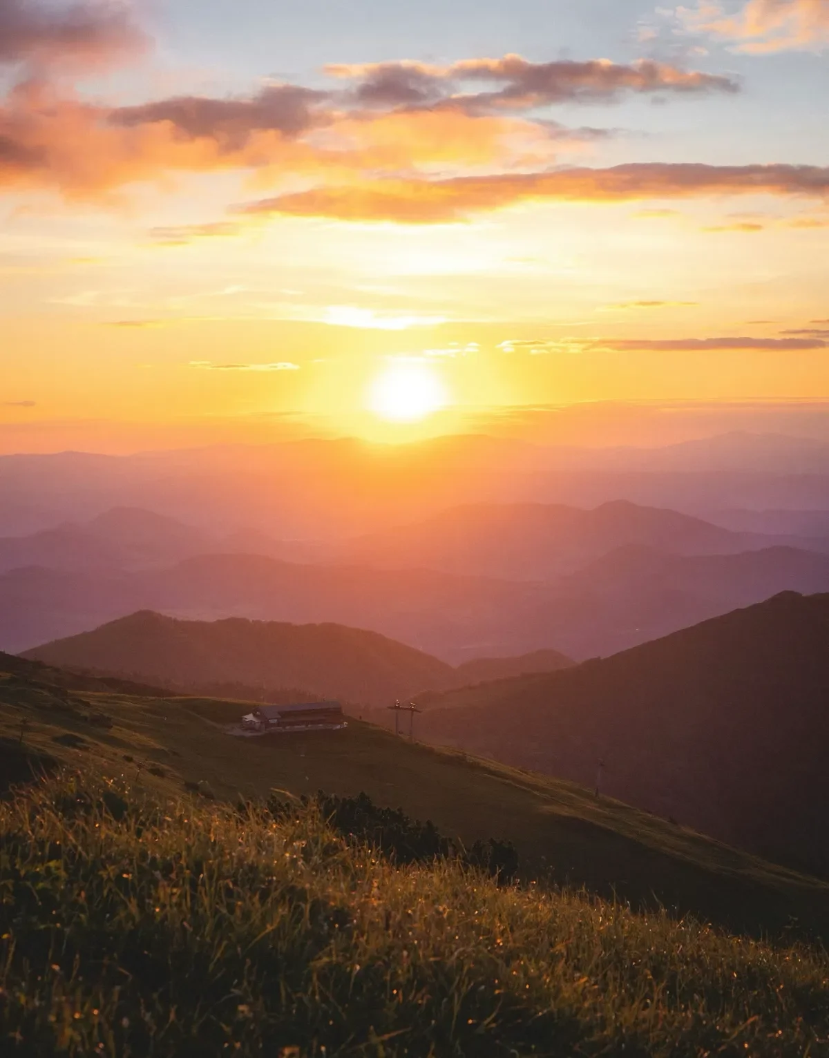 Hazy orange sunset over grassy mountains
