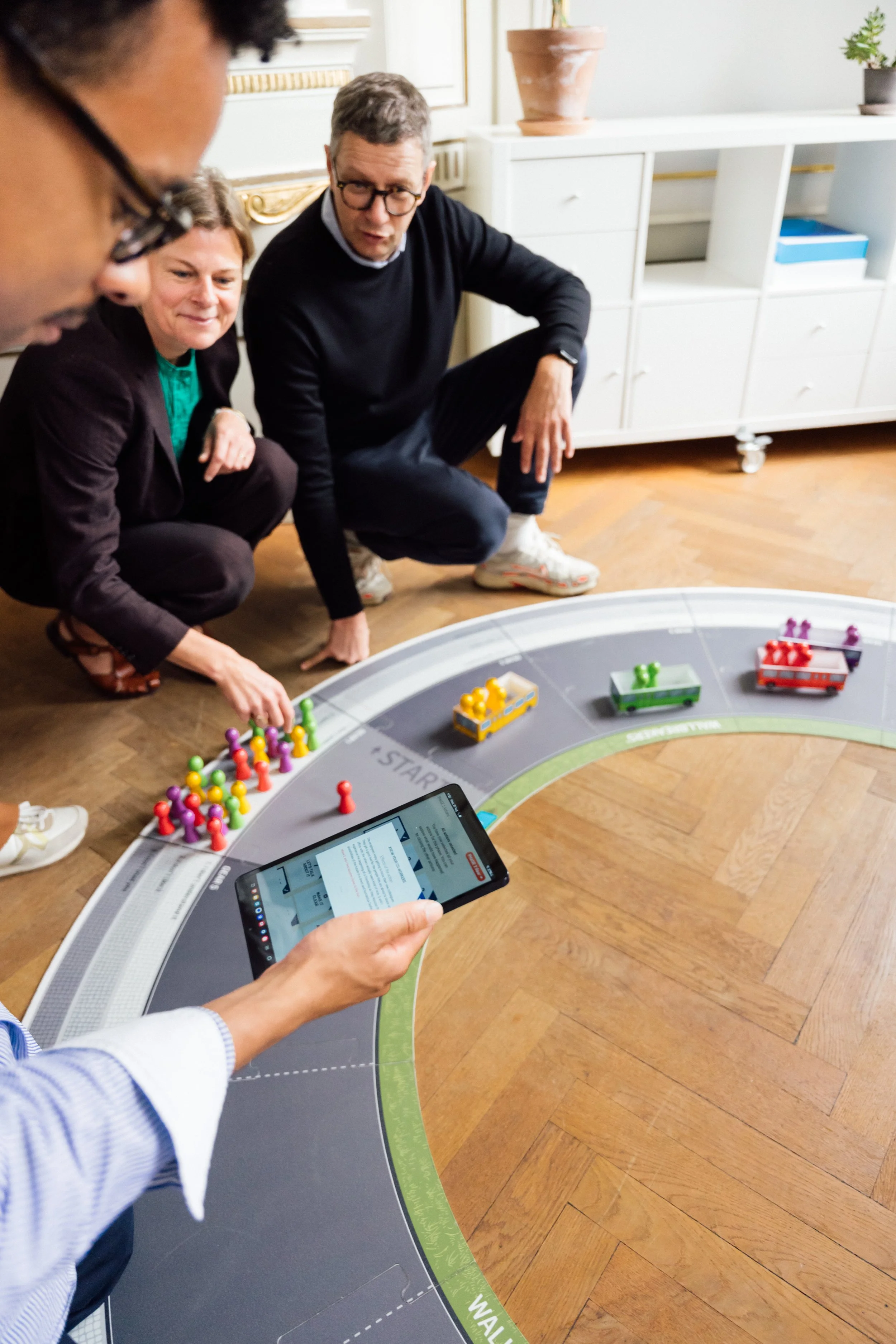 People playing a business change simulation, while one person uses a smartphone to view information.