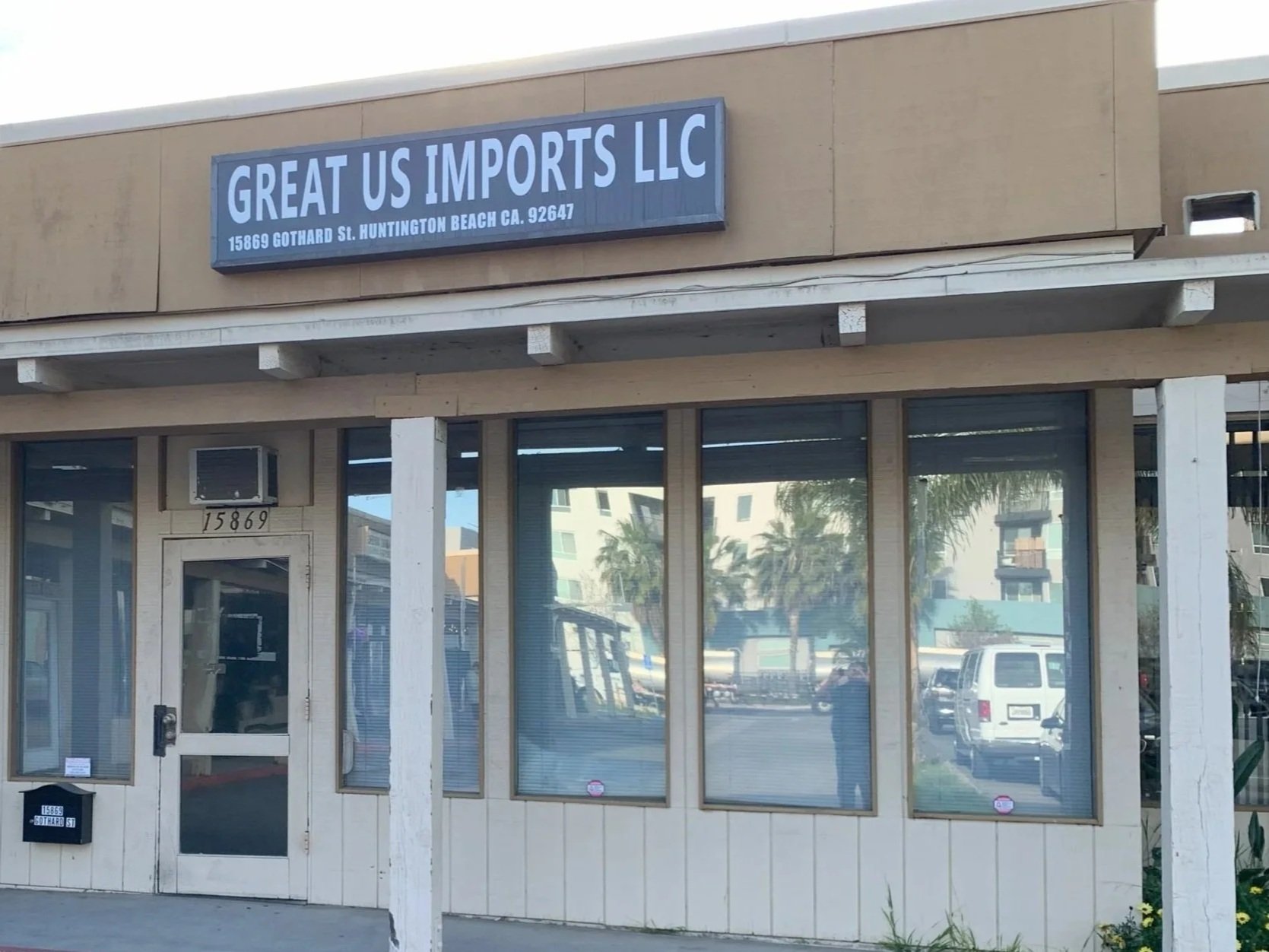 Storefront with a sign that reads "Great US Imports LLC" at 15869 Gothard St., Huntington Beach, California. The storefront has large windows and a glass door, with numbered addressing above the door.