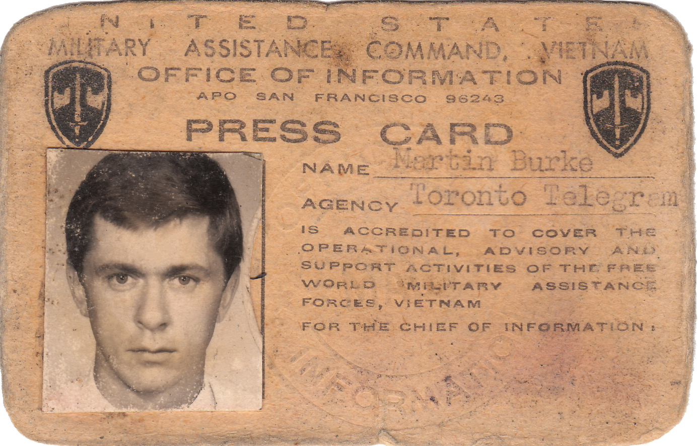 Vintage press card for Martyn Burke, a young man with dark hair, identified as a member of the Toronto Telegram agency, issued by the Office of Information for the U.S. military assistance in Vietnam, with a badge or emblem on the top corners.