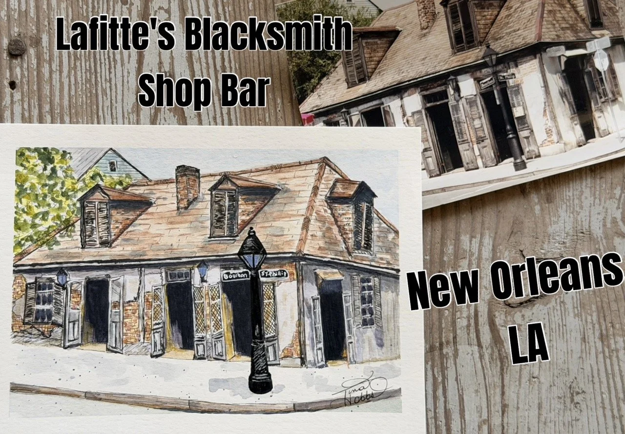A watercolor painting of a corner shop named Lafayette's Blacksmith Shop Bar located in New Orleans, LA, with a street sign reading 'Bourbon' and 'Strand'. The painting is on a wooden surface alongside reference photos of similar buildings.