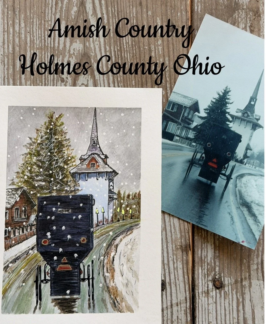 An illustrated postcard of a black train on snowy tracks in Amish Country, Holmes County, Ohio, with a church and snow-covered trees in the background, laid on a wooden surface next to a photograph of a black train on snowy tracks.