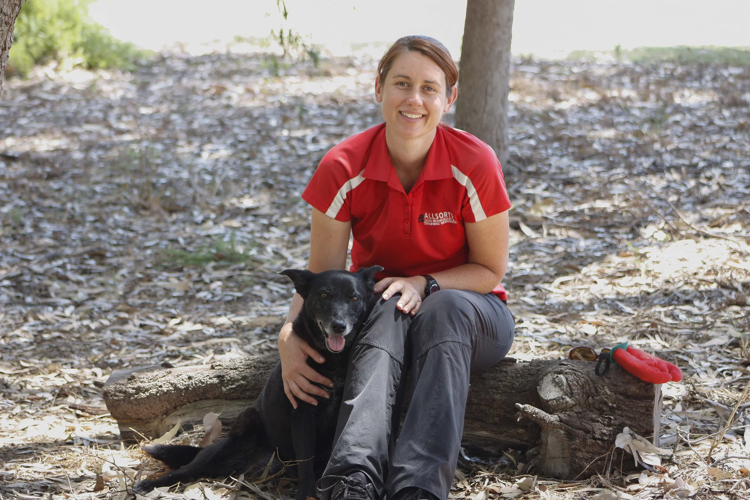 Dog trainer, Debbie Coleman sitting with with a black dog beside her.