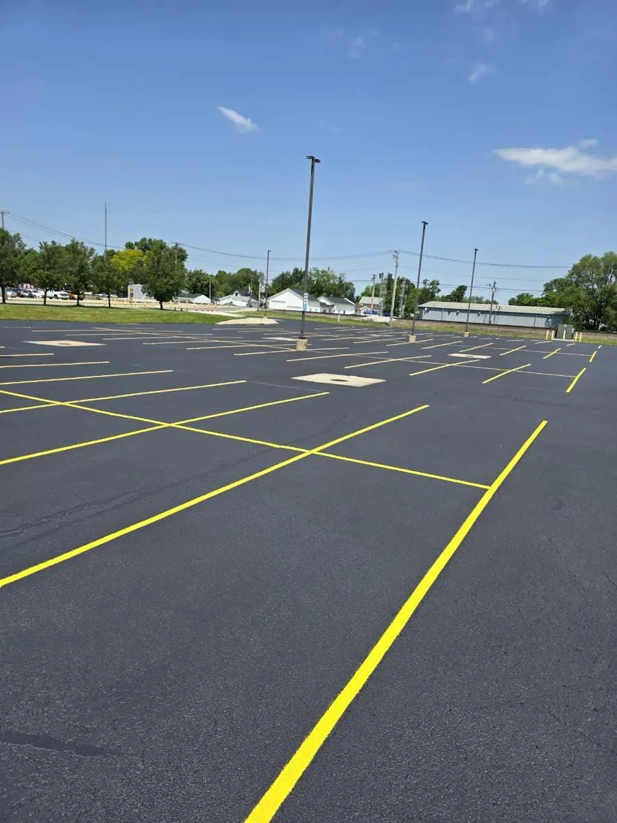 Empty parking lot with freshly painted yellow parking lines and a clear blue sky.