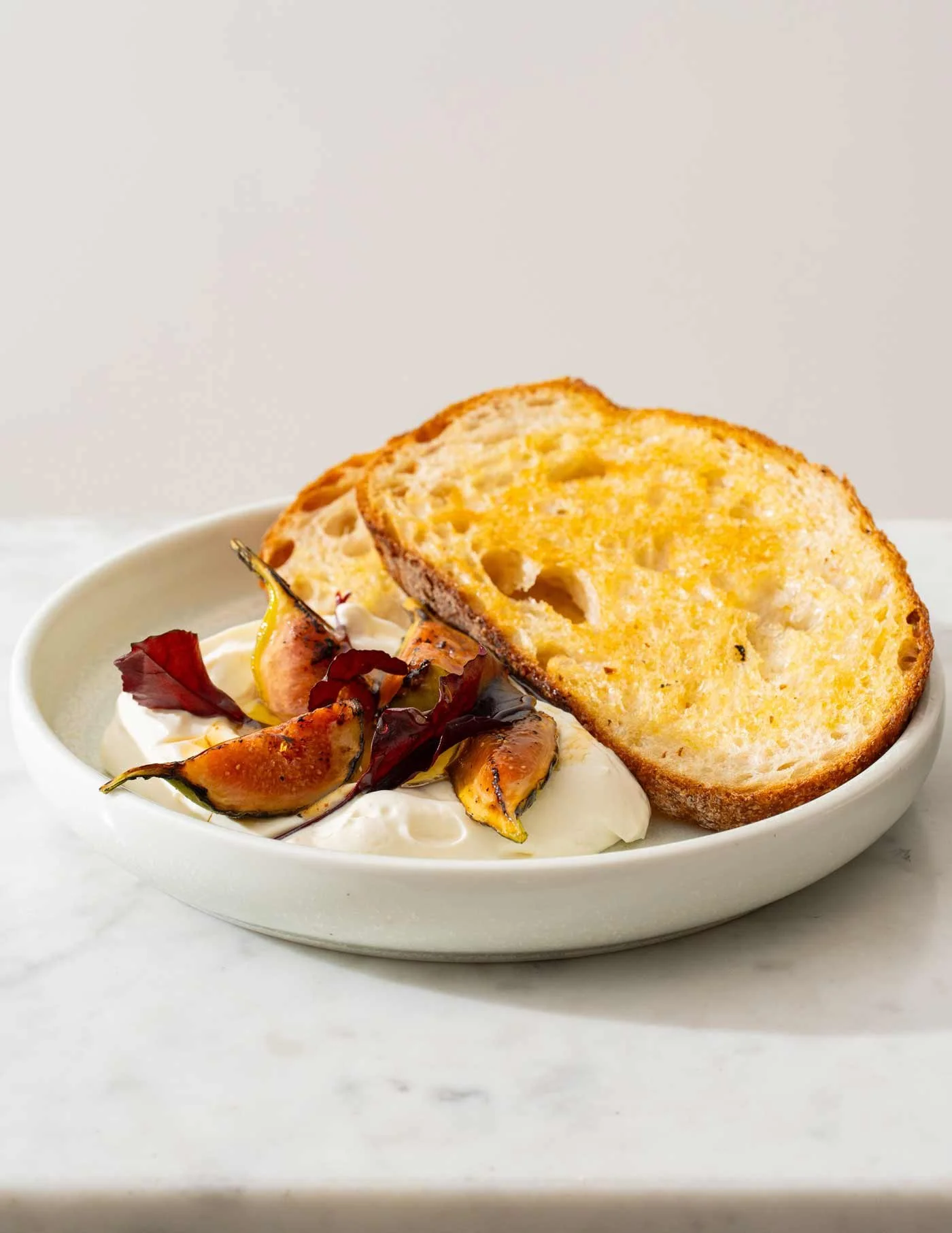 Bowl of creamy dip topped with grilled vegetables and two slices of toasted bread.
