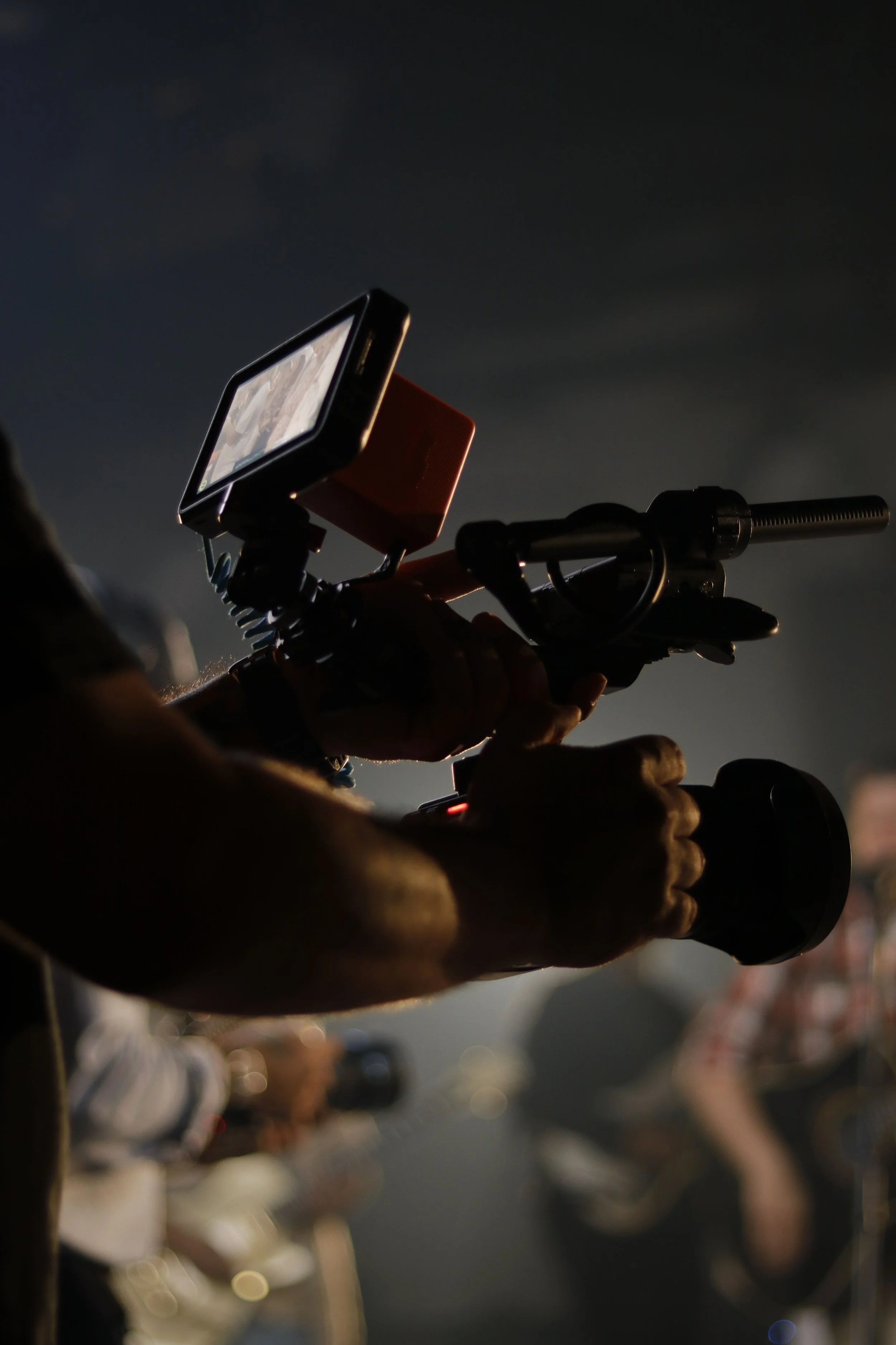Close-up of a person holding a smartphone mounted on a bike handlebar. The background is dark with blurry lights and people.