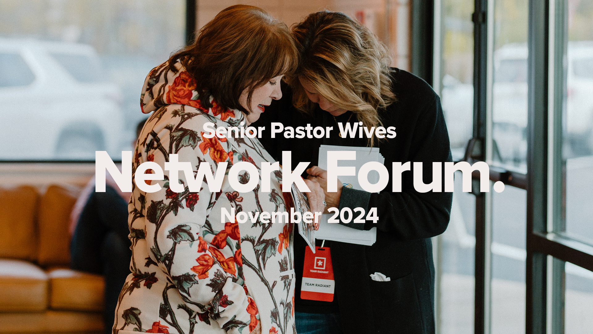 Two women with bowed heads, hold hands in prayer. Promotion for Network Forum.