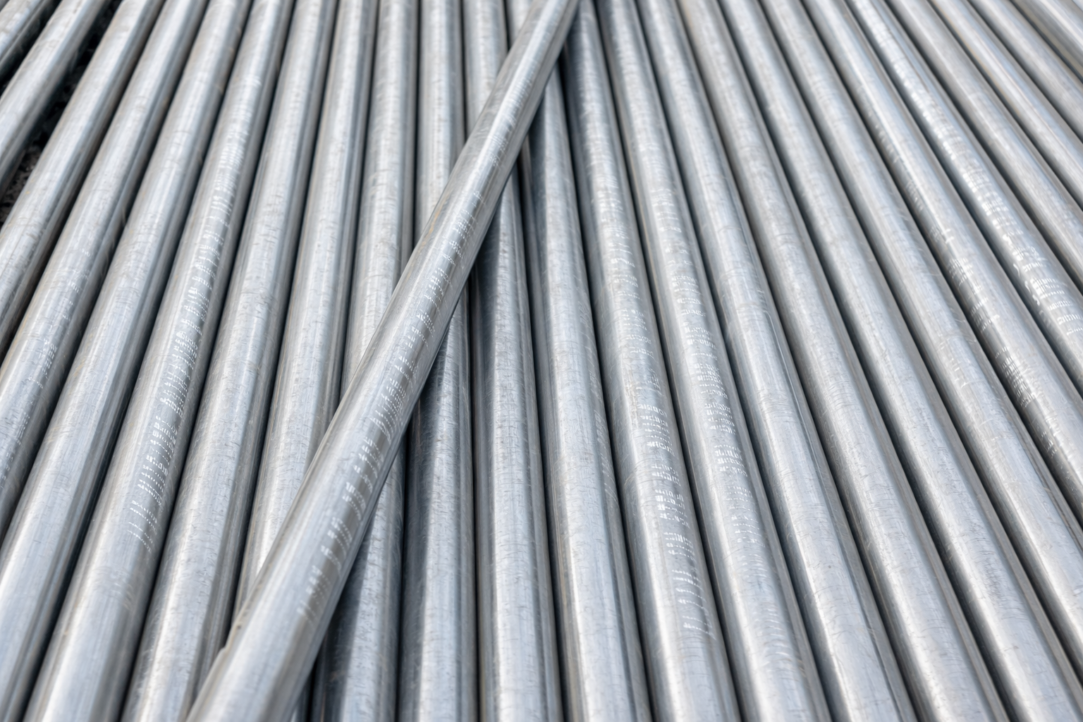 Piles of metal pipes arranged in rows.