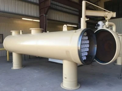 Large industrial heat exchanger or boiler with cylindrical shape and multiple tubes inside, located in a factory or industrial setting.