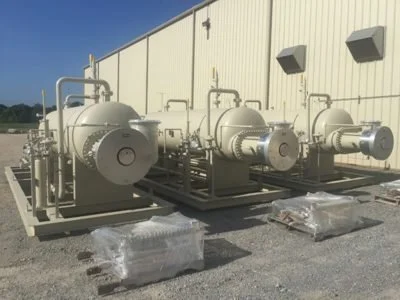 Industrial equipment including large cylindrical tanks and machinery outside a building.