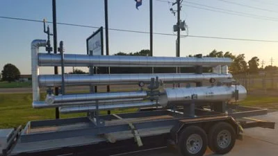 A large industrial water cannon mounted on a trailer parked outdoors at sunset.