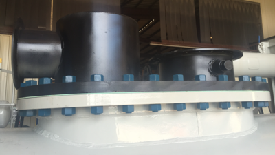 Close-up of industrial machinery component with a large black cylindrical part on top, a white base, and blue bolts around the perimeter.