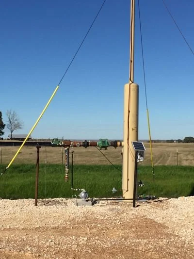 A solar-powered weather station with antennas and sensors set up on a grassy field.