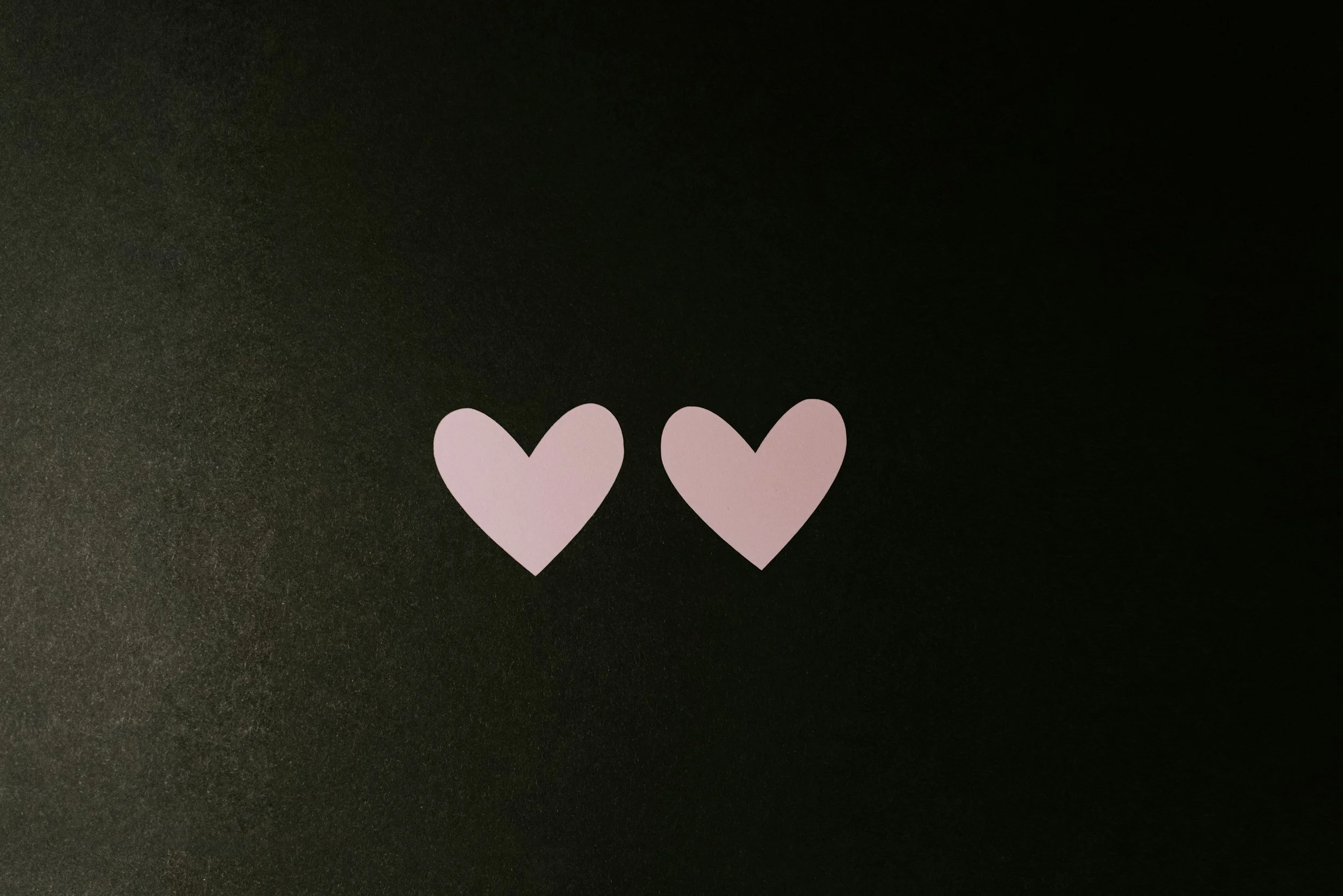 Two purple paper hearts on a black background.