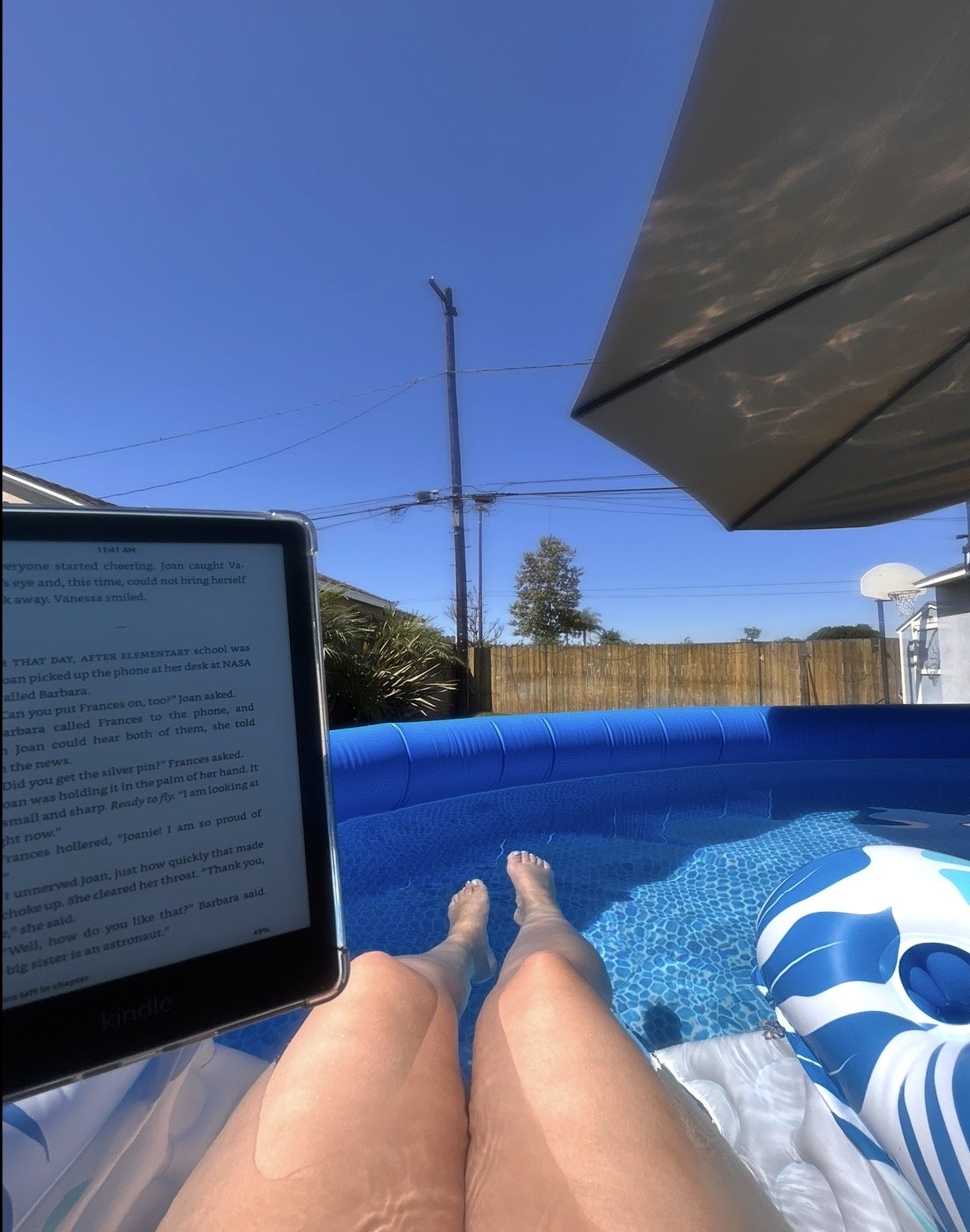 Drea reading on her Kindle outside with a clear blue sky in the background