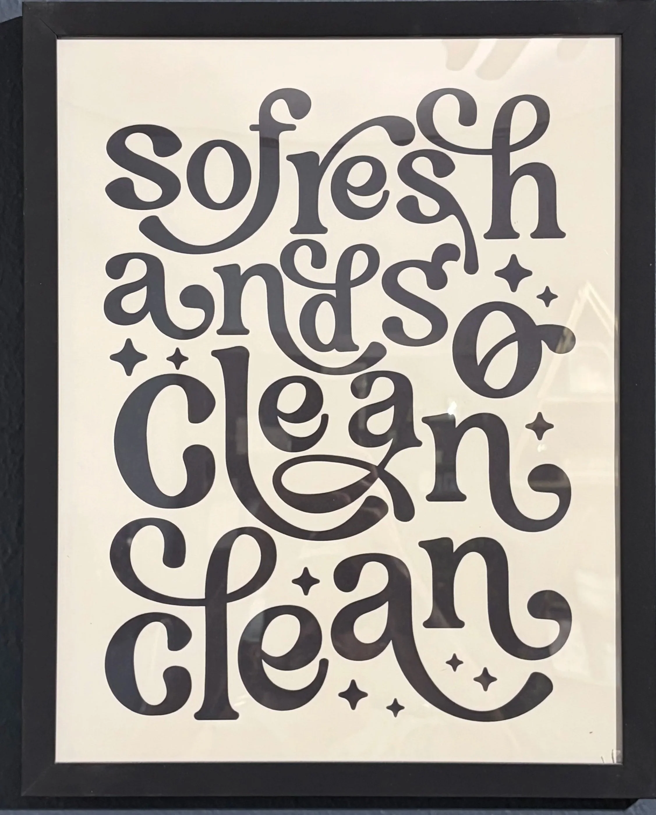Decorative framed sign with the phrase "fresh and tasty" written in stylized black lettering on a white background, accented with small star shapes.