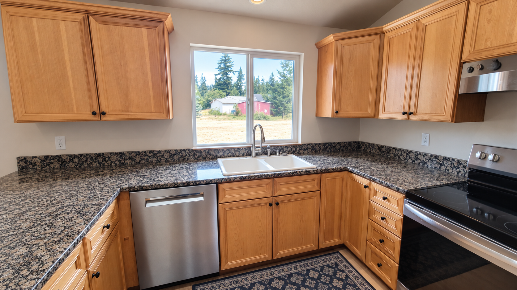 Bright kitchen with oak cabinets, granite countertops, double sink beneath a window, stainless steel dishwasher, and electric range