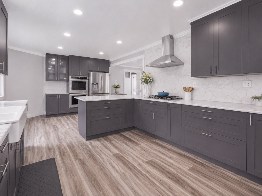 Modern kitchen with gray cabinets, white marble countertops, a stainless steel range hood, built-in oven, refrigerator, and honeycomb tile backsplash.