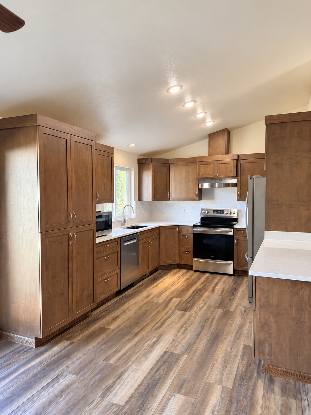 Modern kitchen with dark wood cabinets, stainless steel appliances, white countertops, breakfast bar, and wood-look flooring