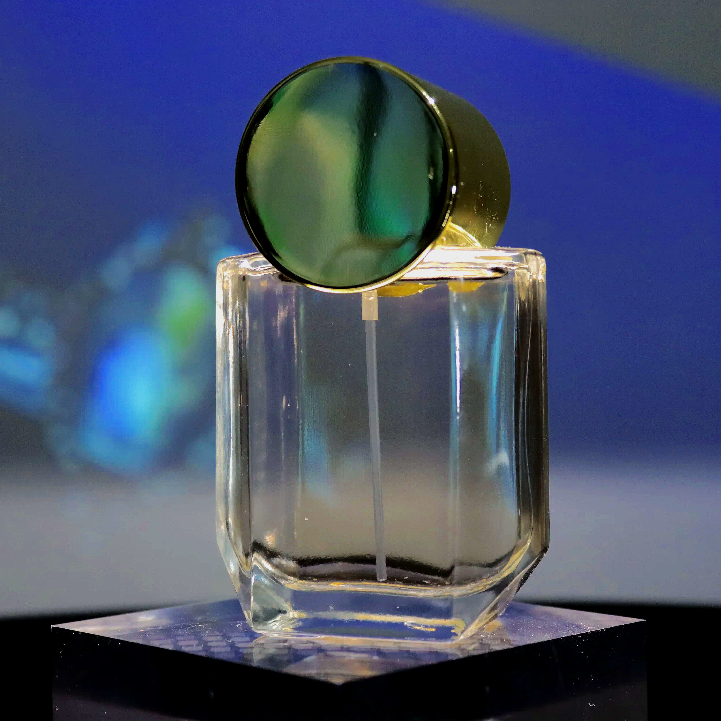 A close-up of a clear glass, with a reflective surface, placed on a flat surface with a dark background. The glass appears to be empty and is captured in a way that highlights its transparency and reflections.