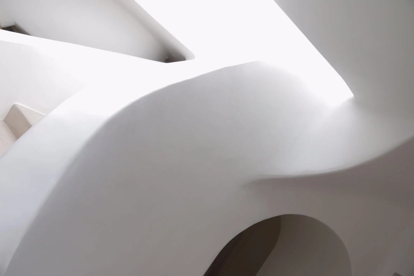 Close-up of a modern, minimalistic white decorative sculpture or object with smooth, curved surfaces and an opening, illuminated by bright light.