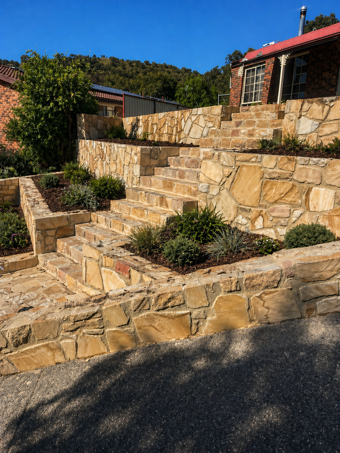 Stone staircase and retaining walls with landscaped plants in a backyard garden.