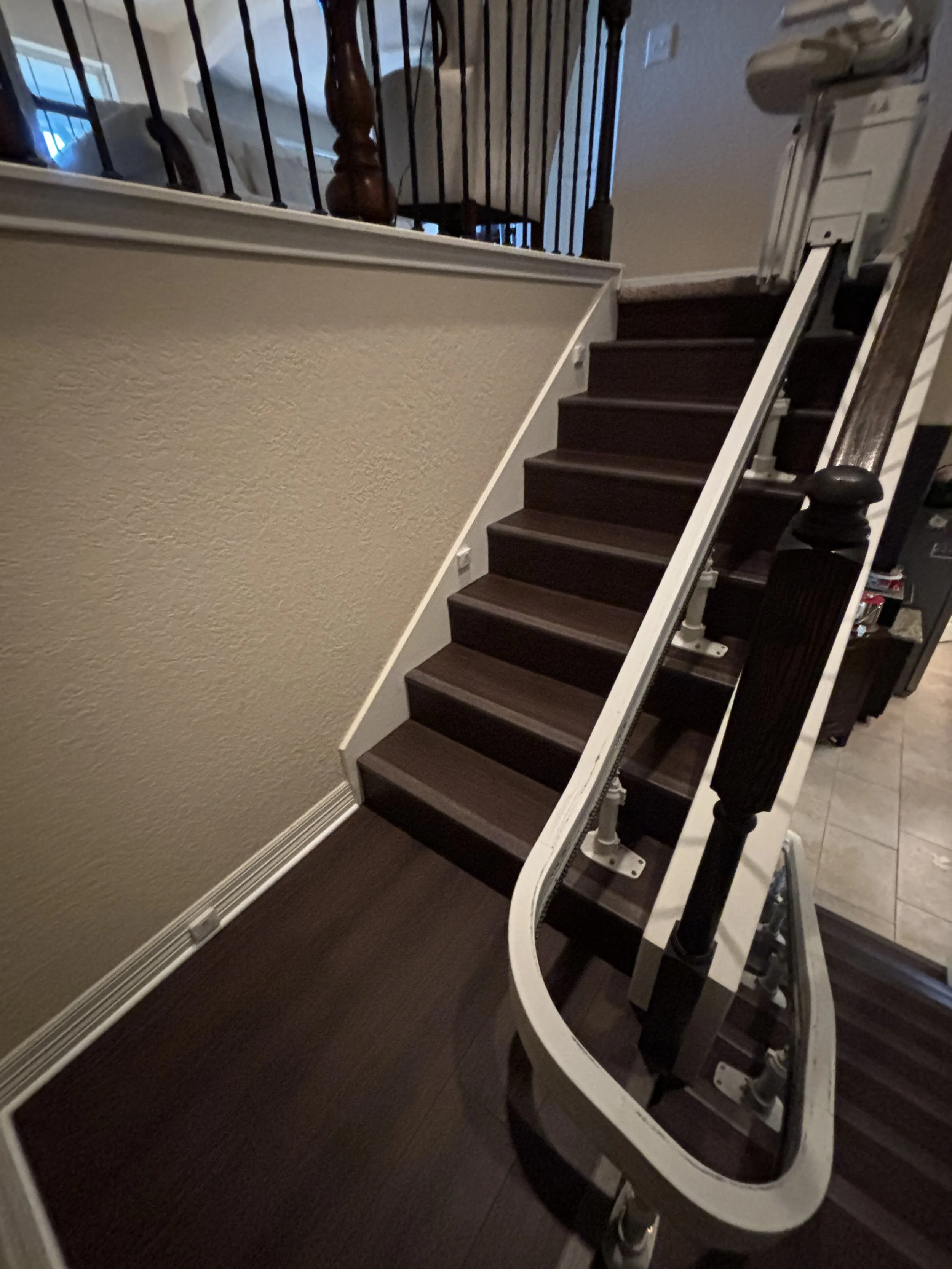 Disassembled staircase with dark wooden steps and white railings, partially taken apart and leaning against the wall.