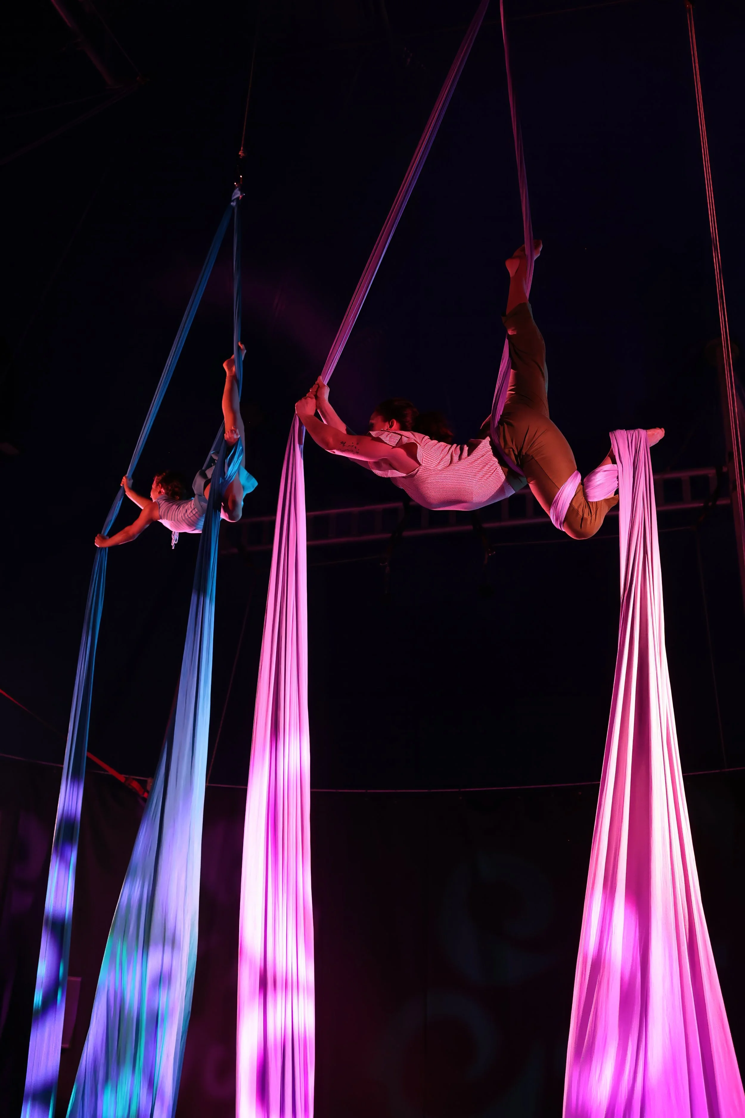 Two aerialists perform on aerial silks