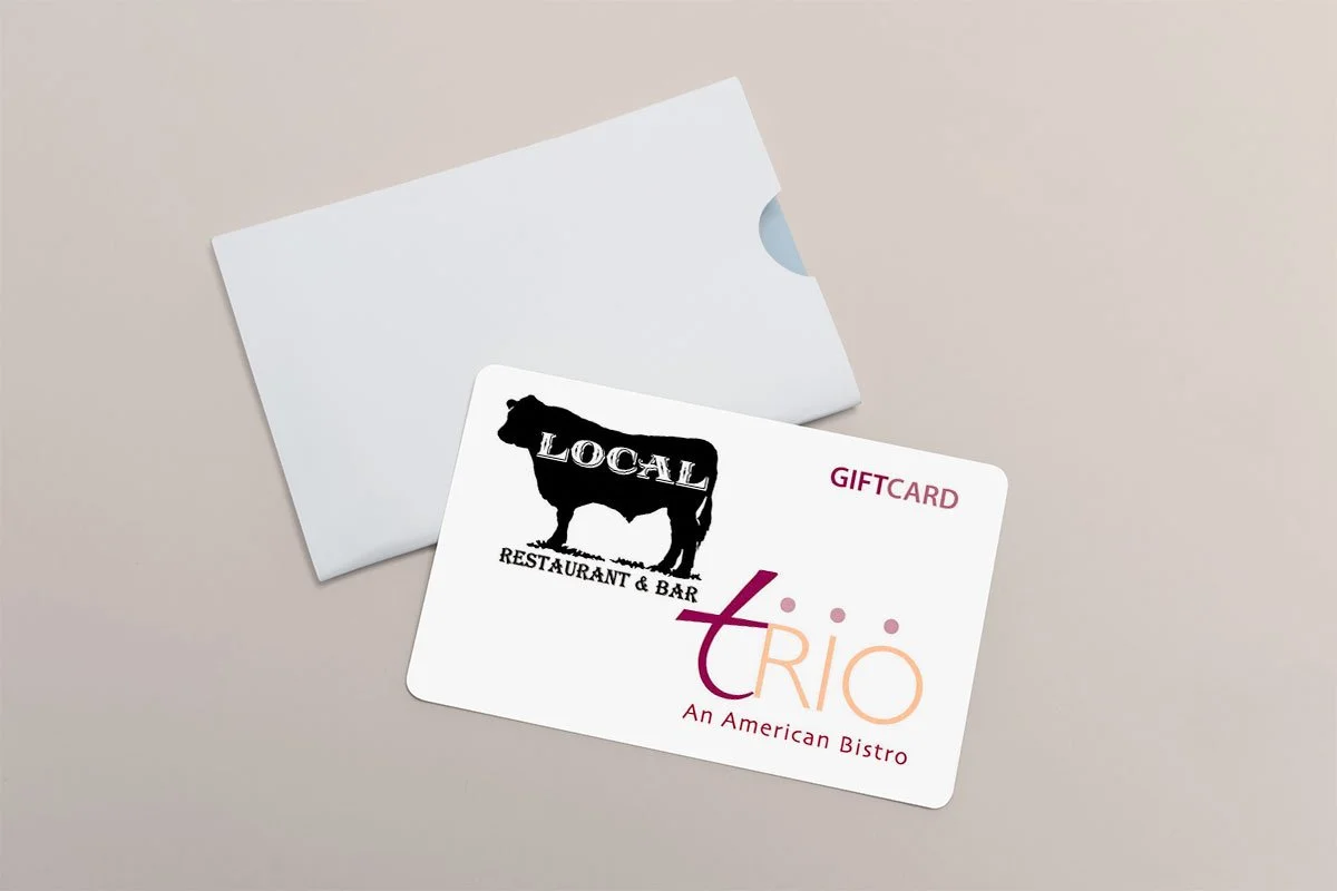 A white gift card with the logo and name of a restaurant and bar called Local, featuring a silhouette of a sheep, and the logo and name of Trio, an American bistro, on a light gray background. The card is partially inside a white envelope.