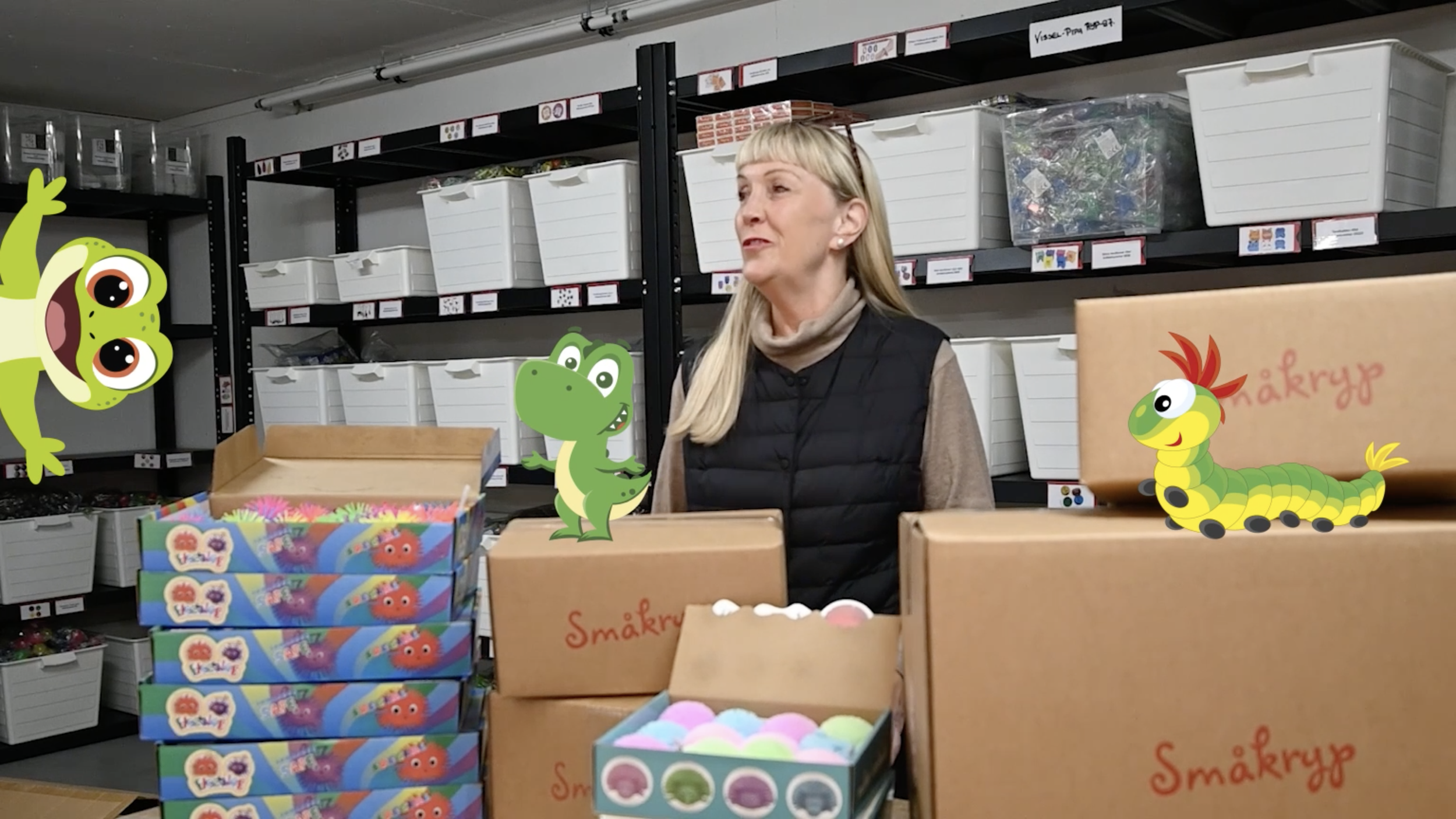 Smakryp video of a woman standing in a storage room surrounded by boxes and shelves filled with supplies. The image is decorated with animated cartoon dinosaur, lizard and a caterpillar.
