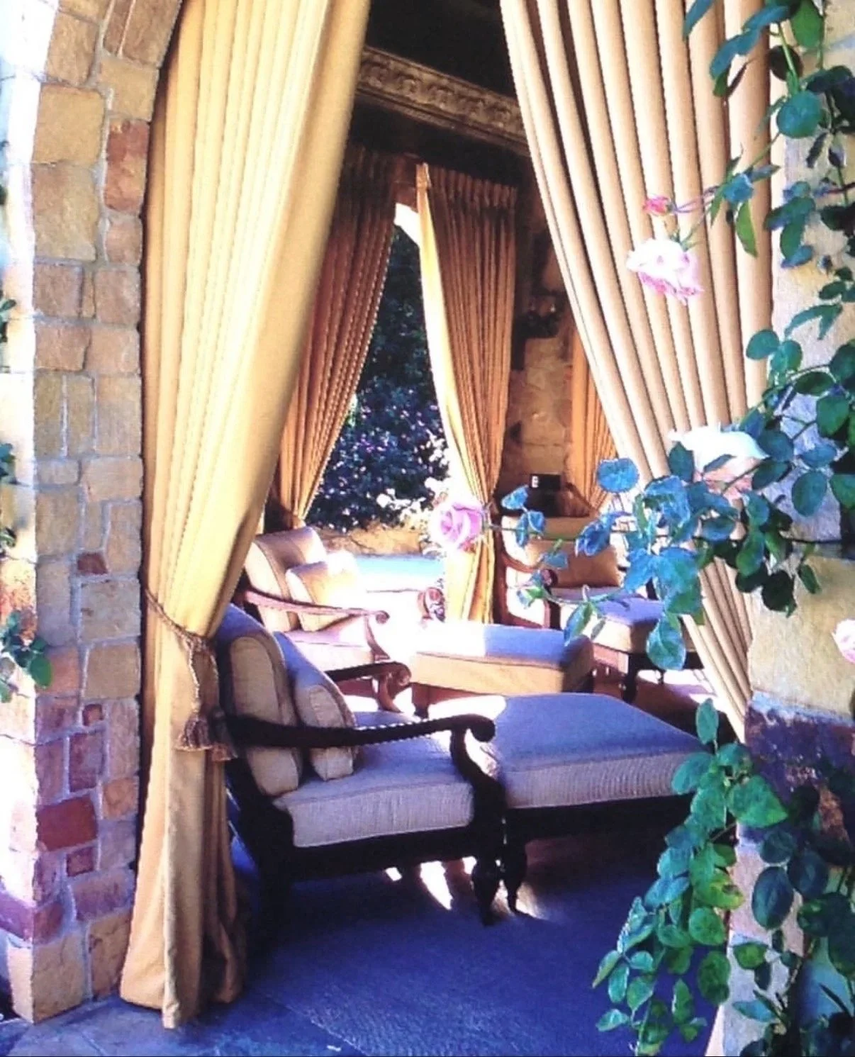 Elegant sitting area with vintage-style chairs, large window with drapery, and flowering plants indoors, possibly in a historic or luxurious building.