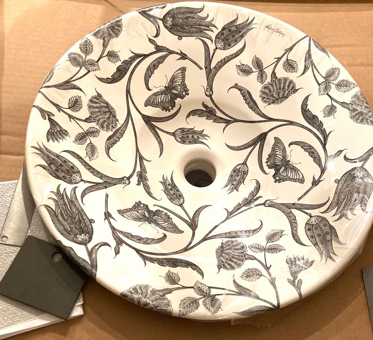 Decorative ceramic sink with black floral and butterfly design.