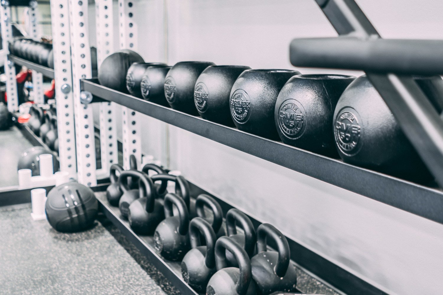 Custom home gym storage with kettlebells, medicine balls, and organized functional fitness equipment on metal rack