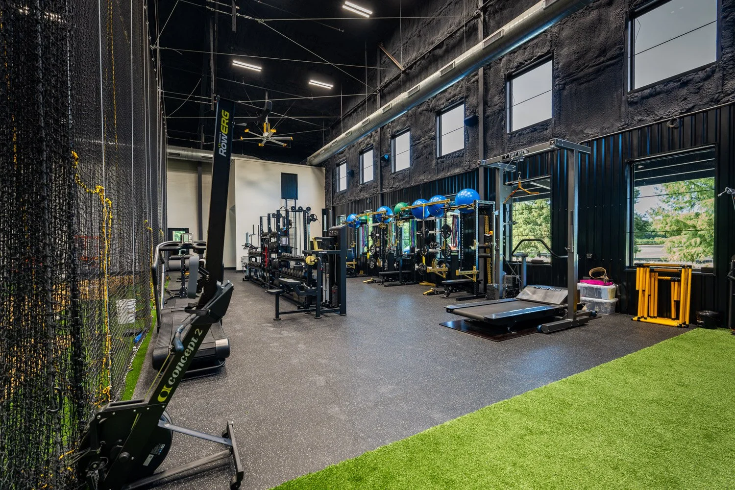 Large custom training facility with Concept2 rowing machine, turf field, strength training equipment, and high ceilings