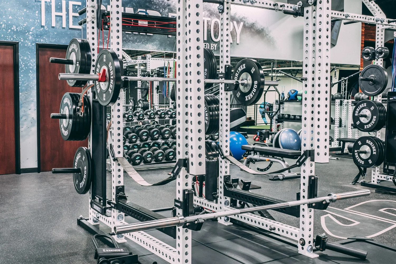 Close-up of Sorinex squat rack with barbell and weight plates in professional strength training gym