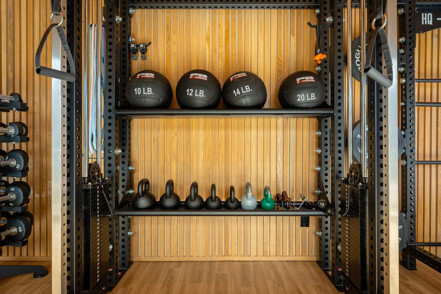 Organized home gym storage with medicine balls, kettlebells, resistance bands, and functional training equipment