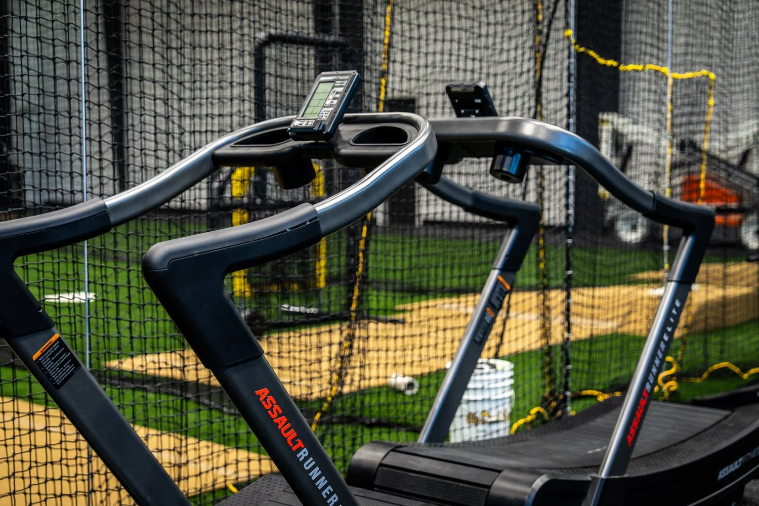 AssaultRunner treadmills in high-performance training facility with turf field and functional fitness space in background