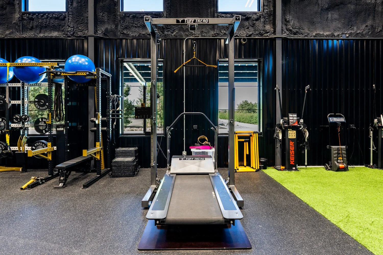 High-performance training gym with Tuff Tread treadmill, strength racks, resistance equipment, and indoor turf area