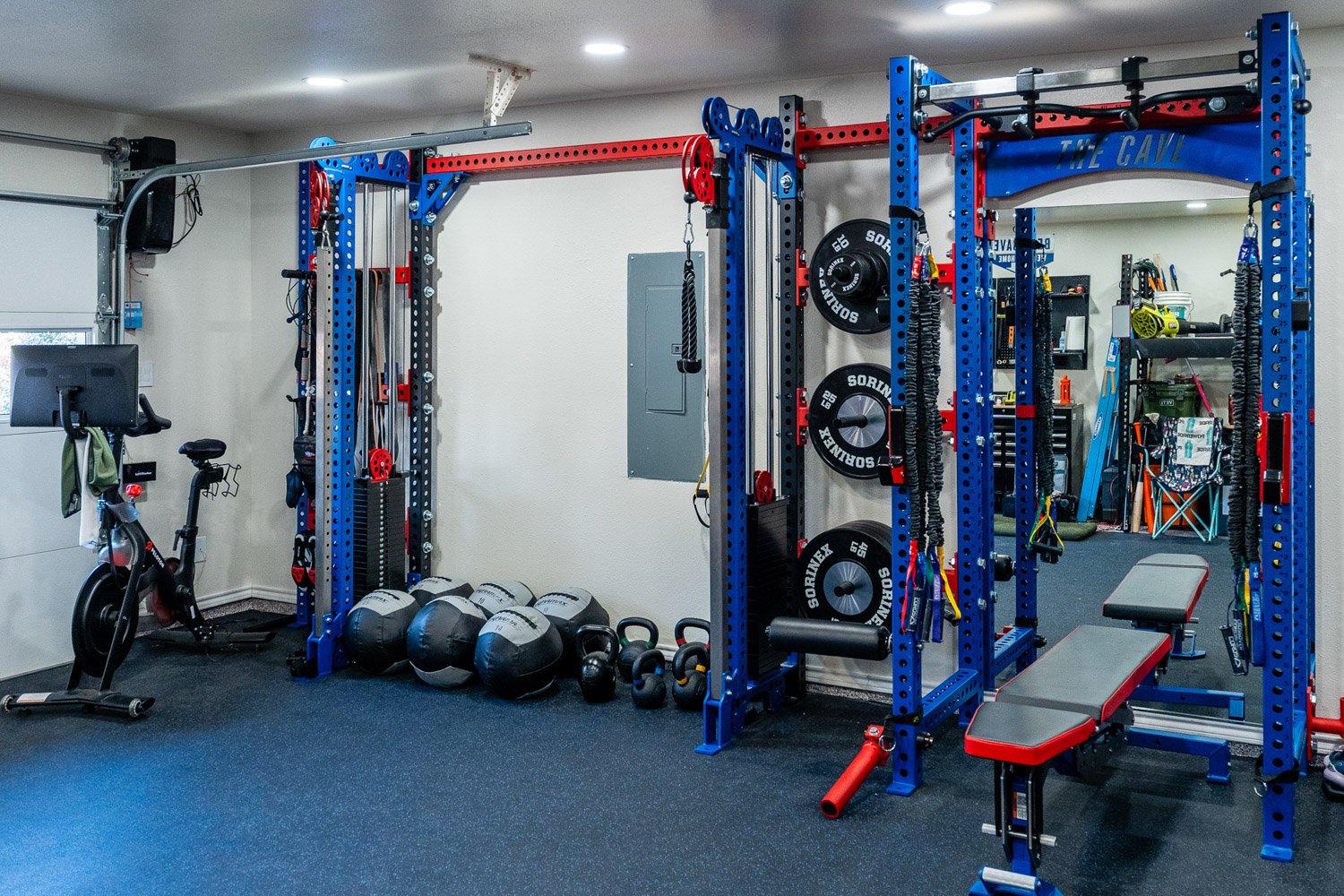 Spacious custom home gym with Sorinex racks, Peloton bike, free weights, and complete strength and cardio training area