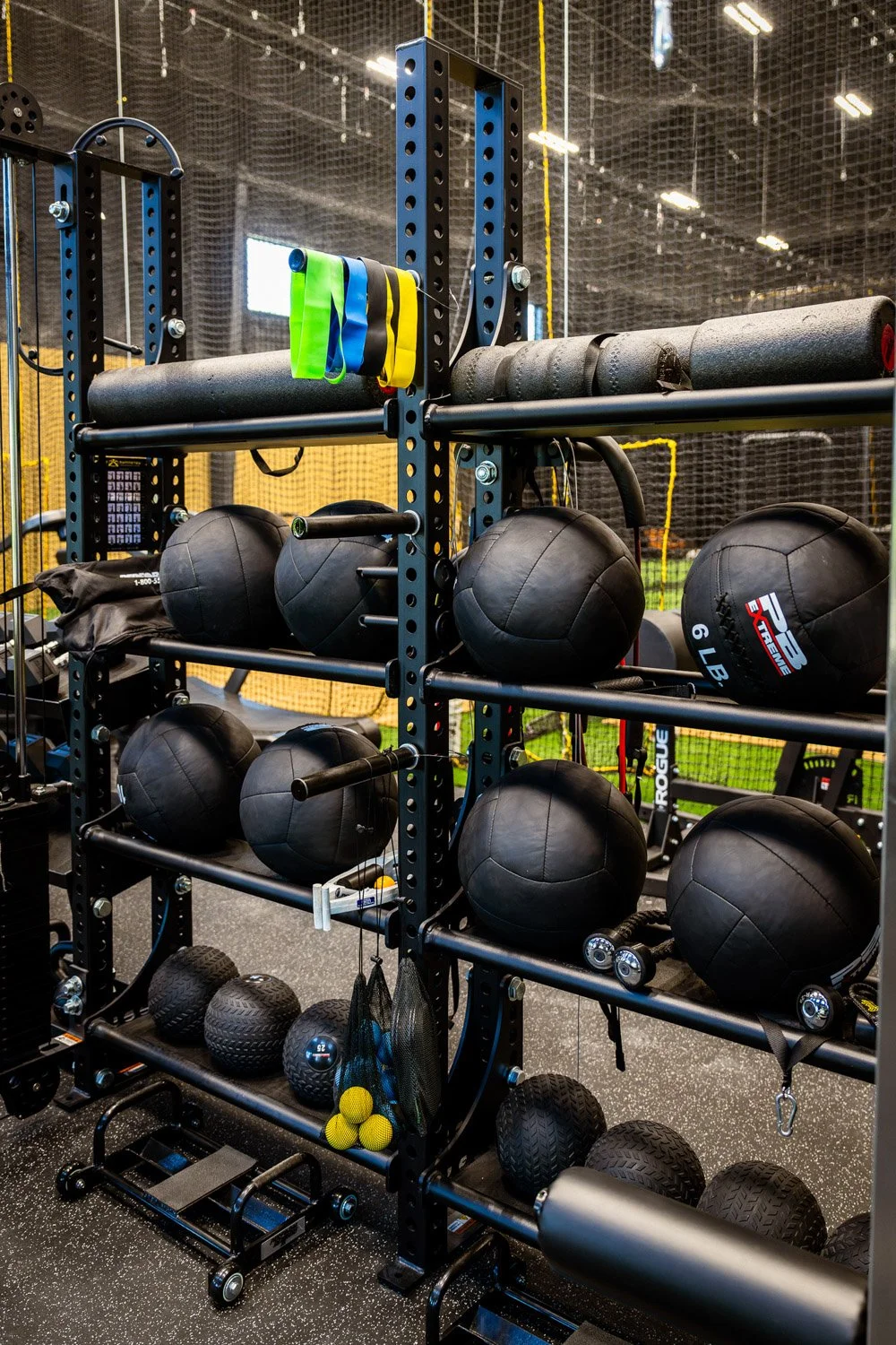 Custom gym storage rack with medicine balls, resistance bands, foam rollers, and functional training equipment in performance gym