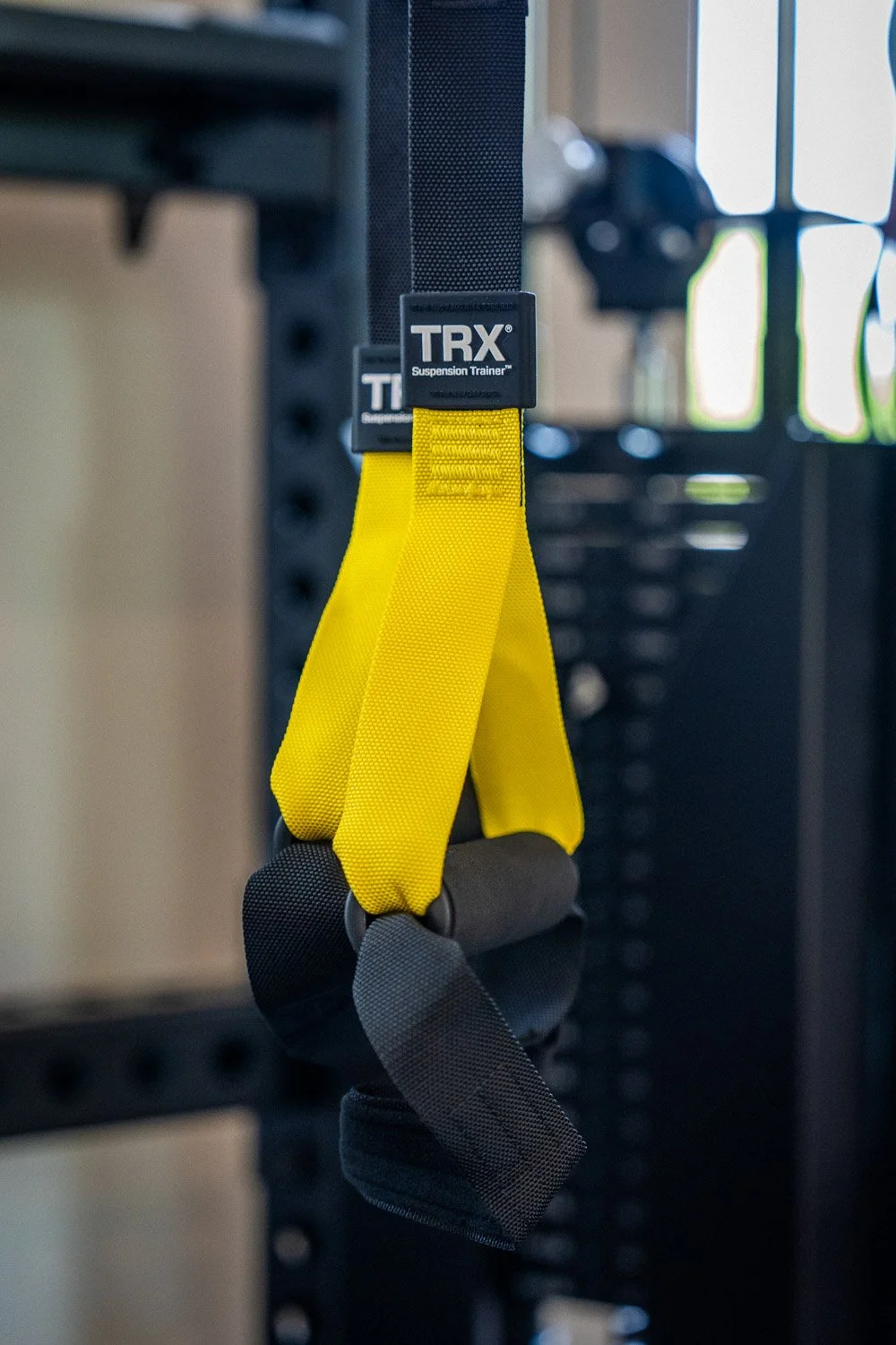 TRX suspension trainer straps hanging from strength equipment in custom home gym for functional training