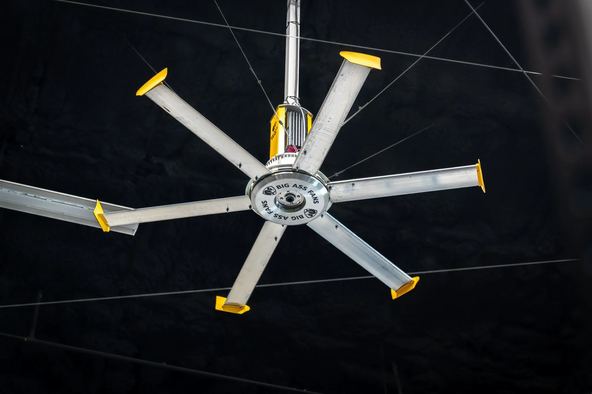 Large industrial ceiling fan in high-performance training facility with exposed ceiling and bright overhead lighting