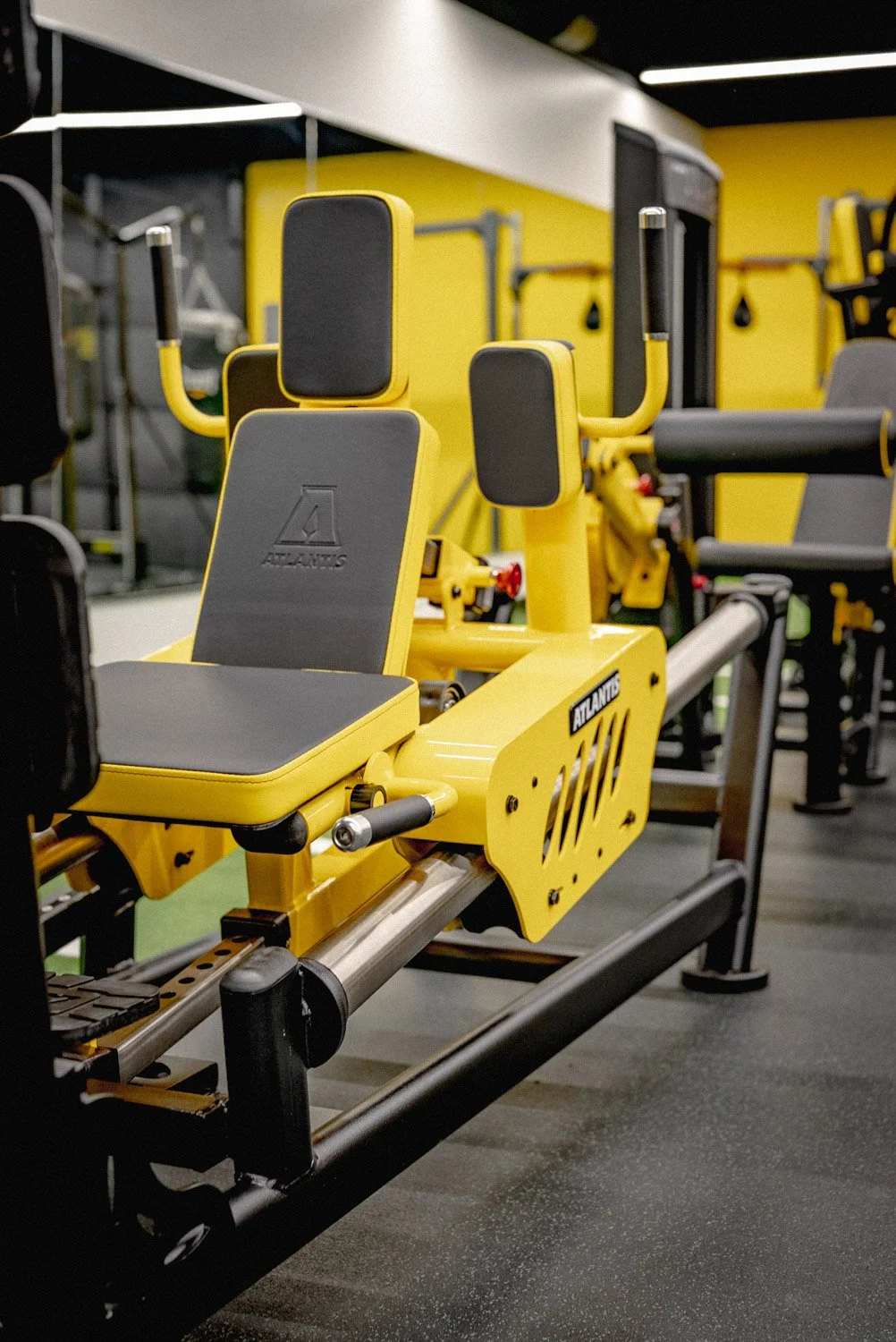 High-end Atlantis strength training machine in custom luxury home gym with modern yellow and black design