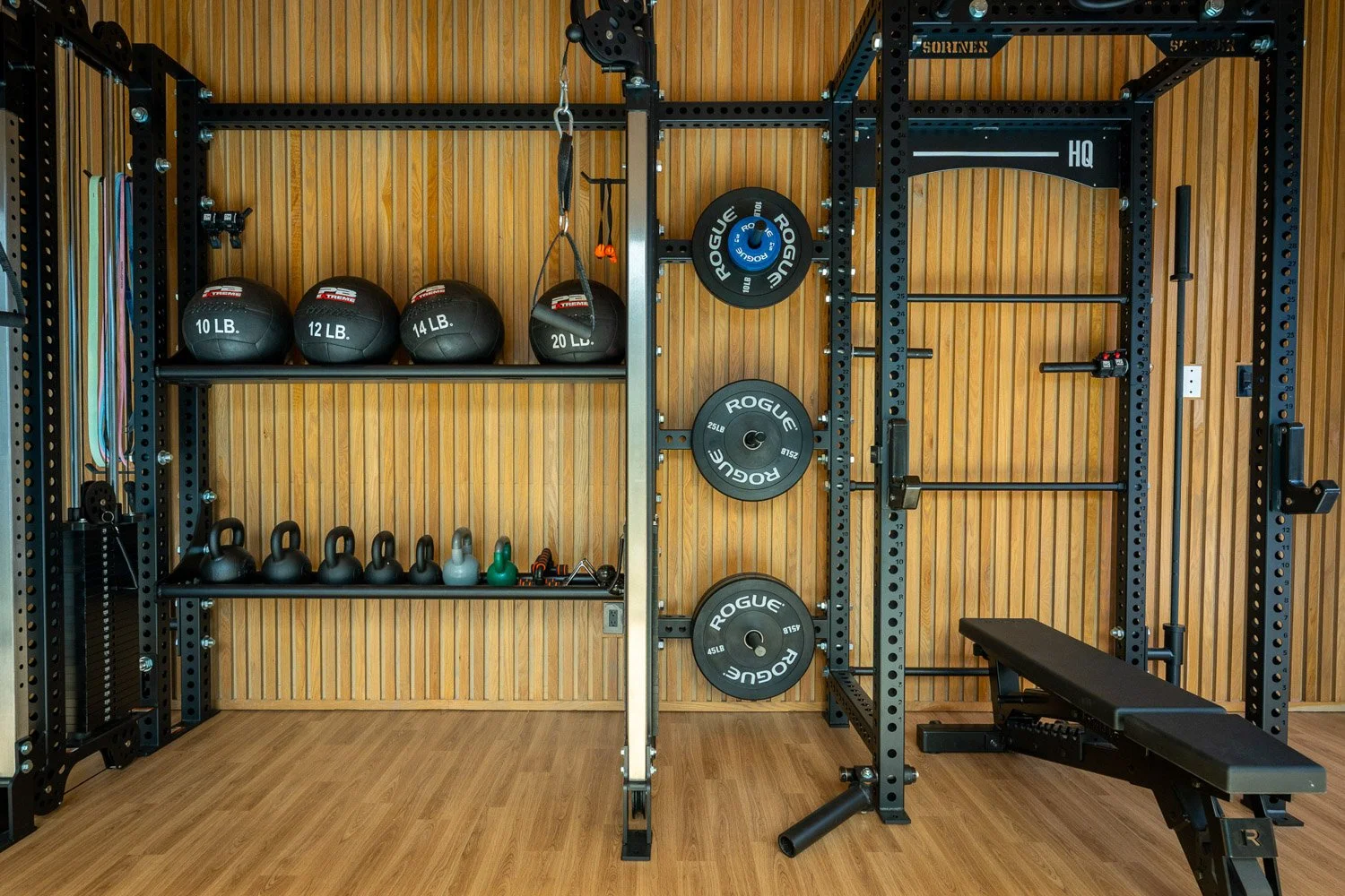 Custom home gym with power rack, adjustable bench, weight plates, and premium strength training equipment with wood panel design