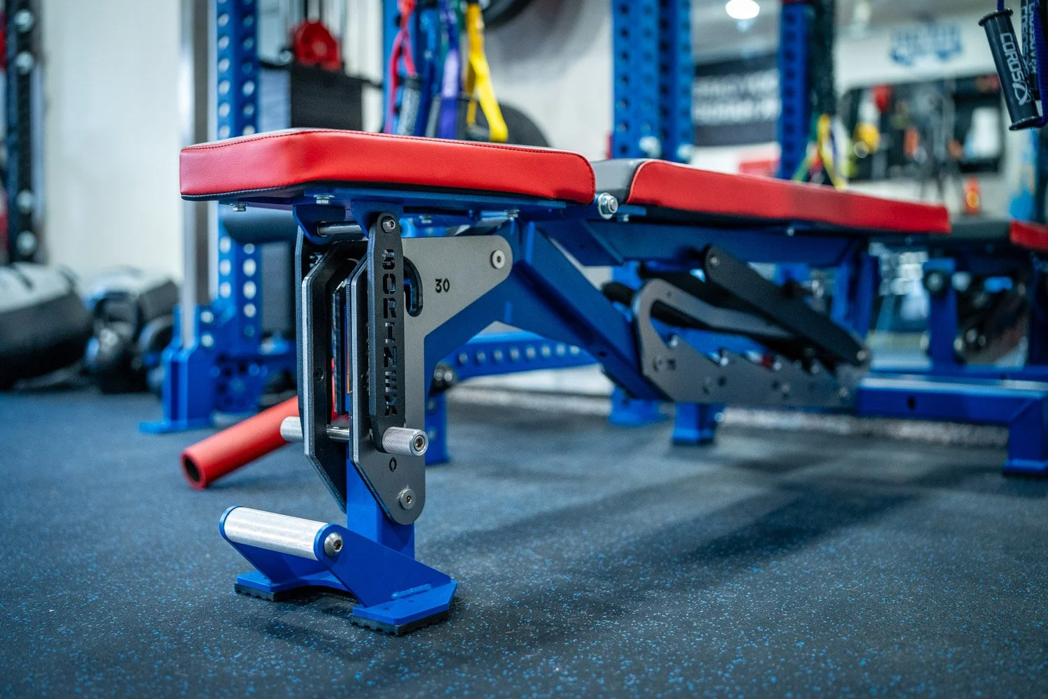 Adjustable workout bench with red padding in modern custom home gym with blue strength equipment
