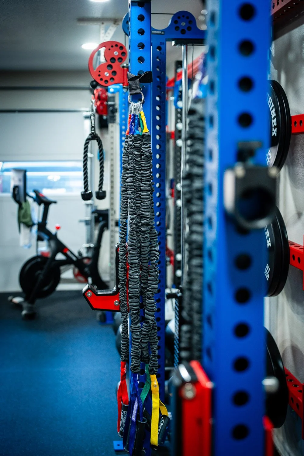 Organized resistance bands and attachments hanging on custom power rack in modern home gym setup