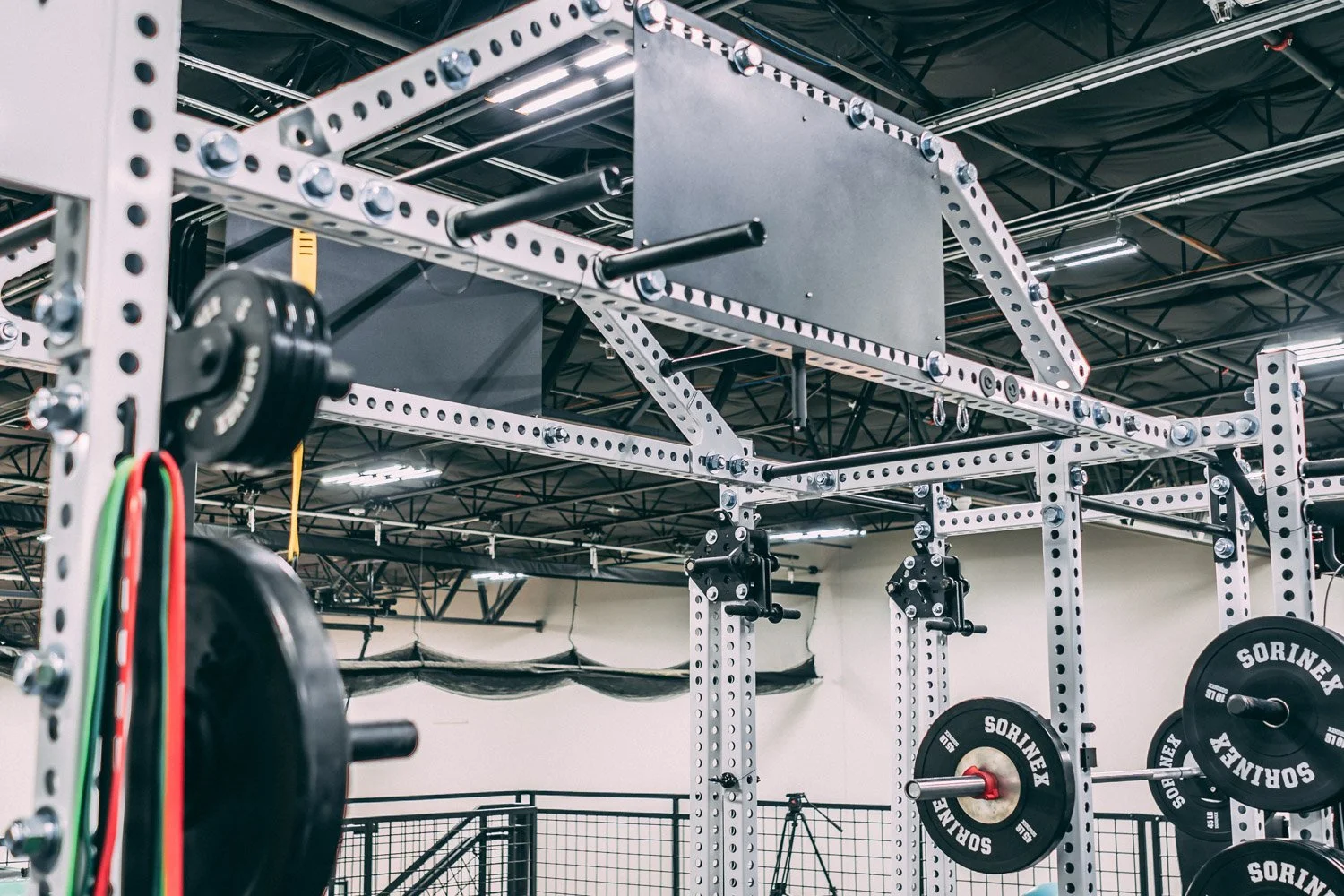 Professional strength training rig with pull-up bars, weight plates, and Sorinex equipment in high-performance gym setup
