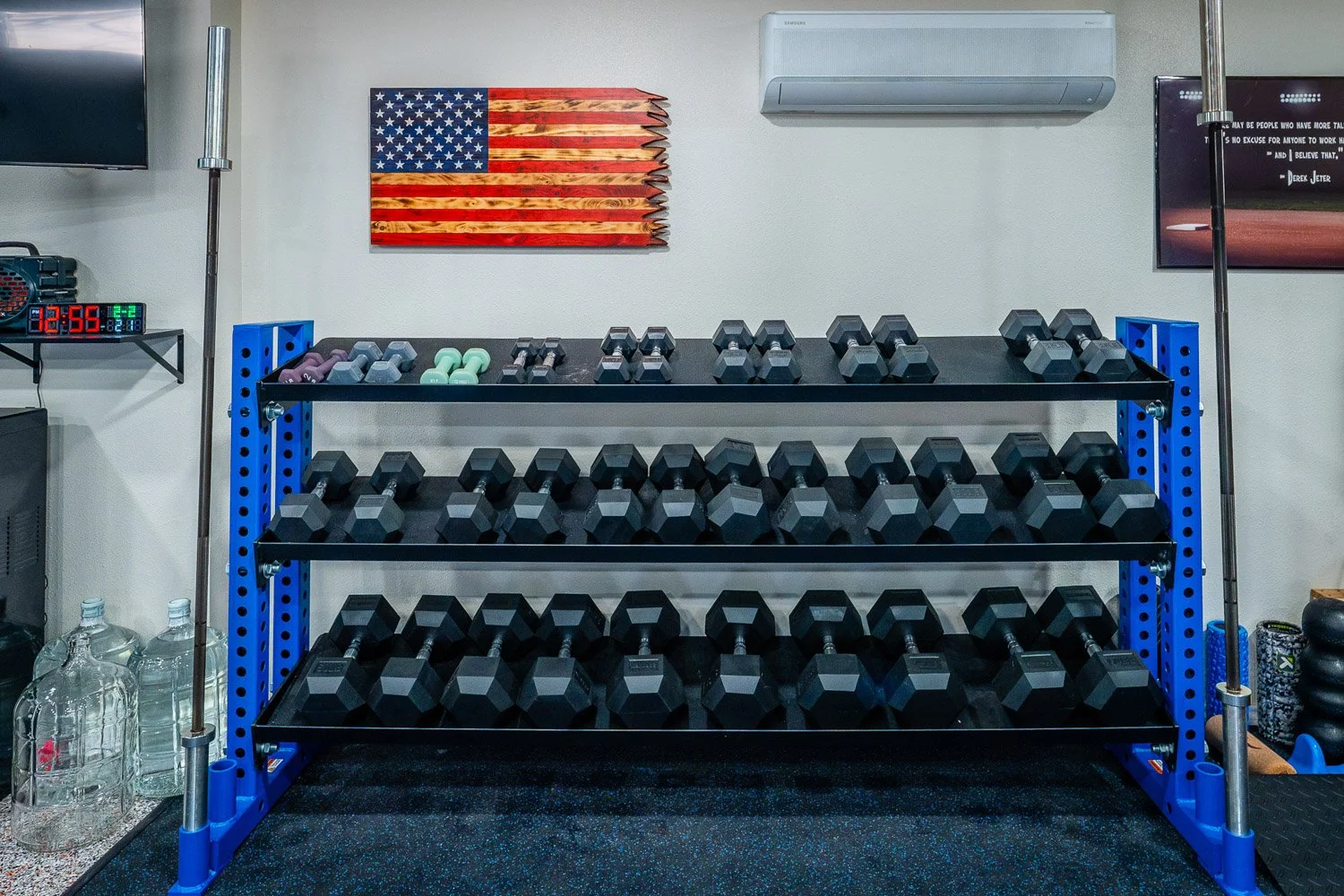 Organized multi-tier dumbbell rack in custom home gym with full free weight set and wall-mounted decor