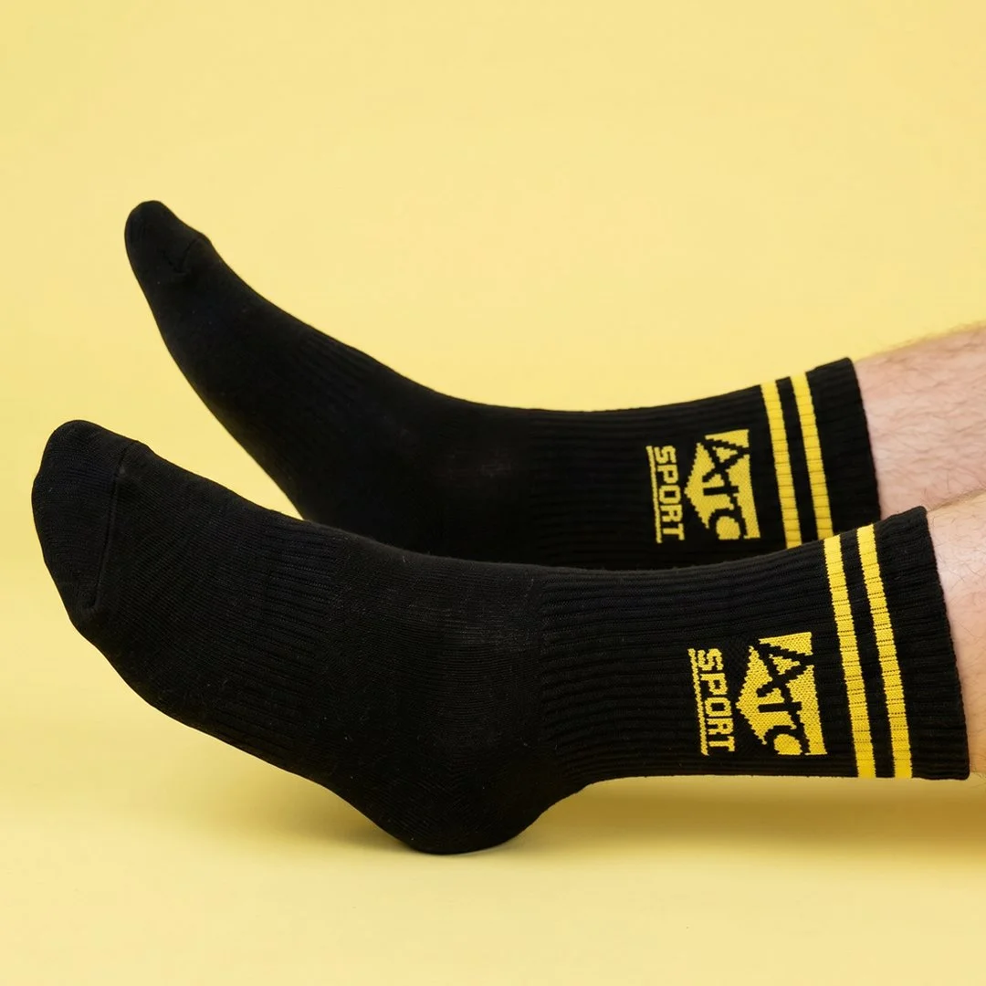 Pair of black athletic socks with yellow stripes and  logo on side