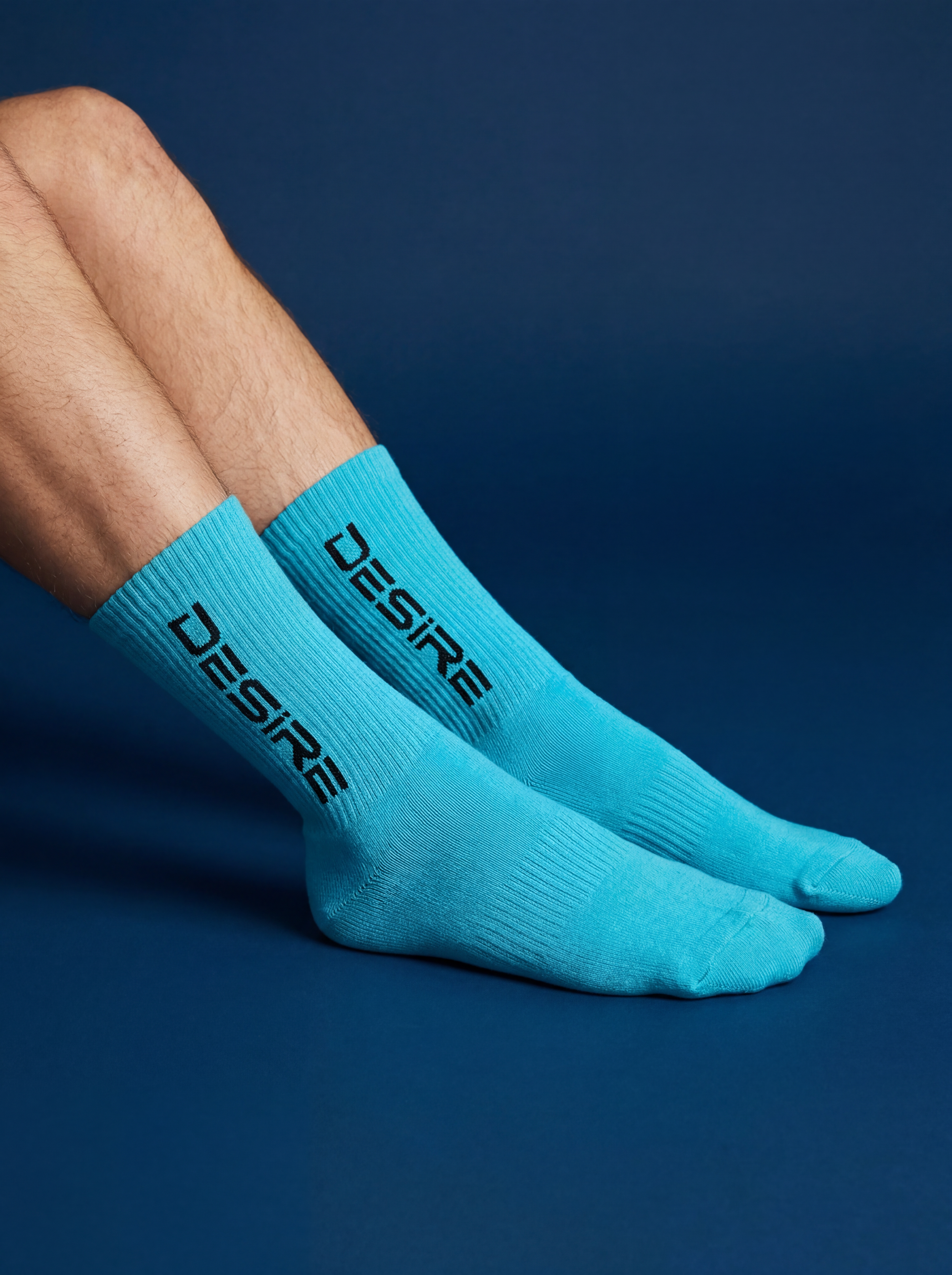 A person wearing blue socks with black text on side of sock, lying on a dark blue background.